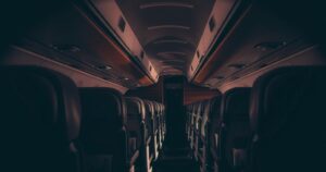 A somber airline scene depicting an empty, dimly lit aircraft interior with dark wooden textures.