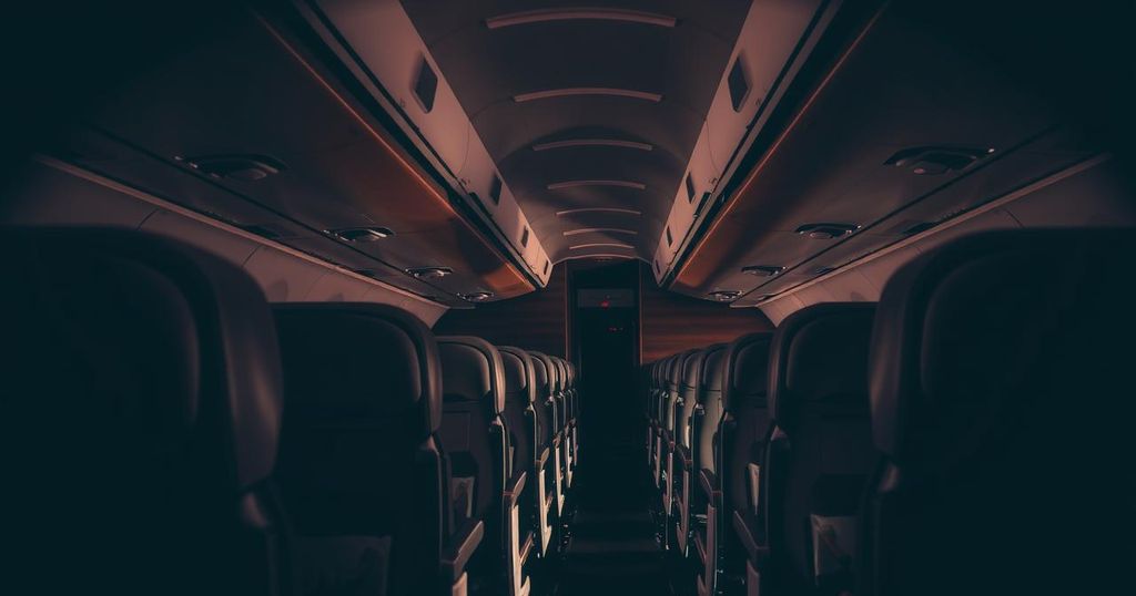 A somber airline scene depicting an empty, dimly lit aircraft interior with dark wooden textures.