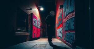 A dark alley with ominous shadows and graffiti symbolizing social unrest and police accountability.