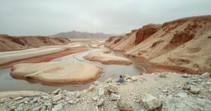 A desolate landscape highlighting water scarcity with dried riverbeds, parched earth, and a neglected water source.