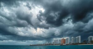 Stormy sky with dark clouds over a coastal cityscape, indicating an approaching tropical storm and weather caution.