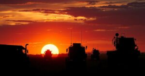 Silhouette of military equipment in a sunset backdrop, showcasing engineering units and demining efforts.